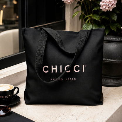 Black tote bag with 'Chicci' branding on a table with a cup of coffee and plant in the background.